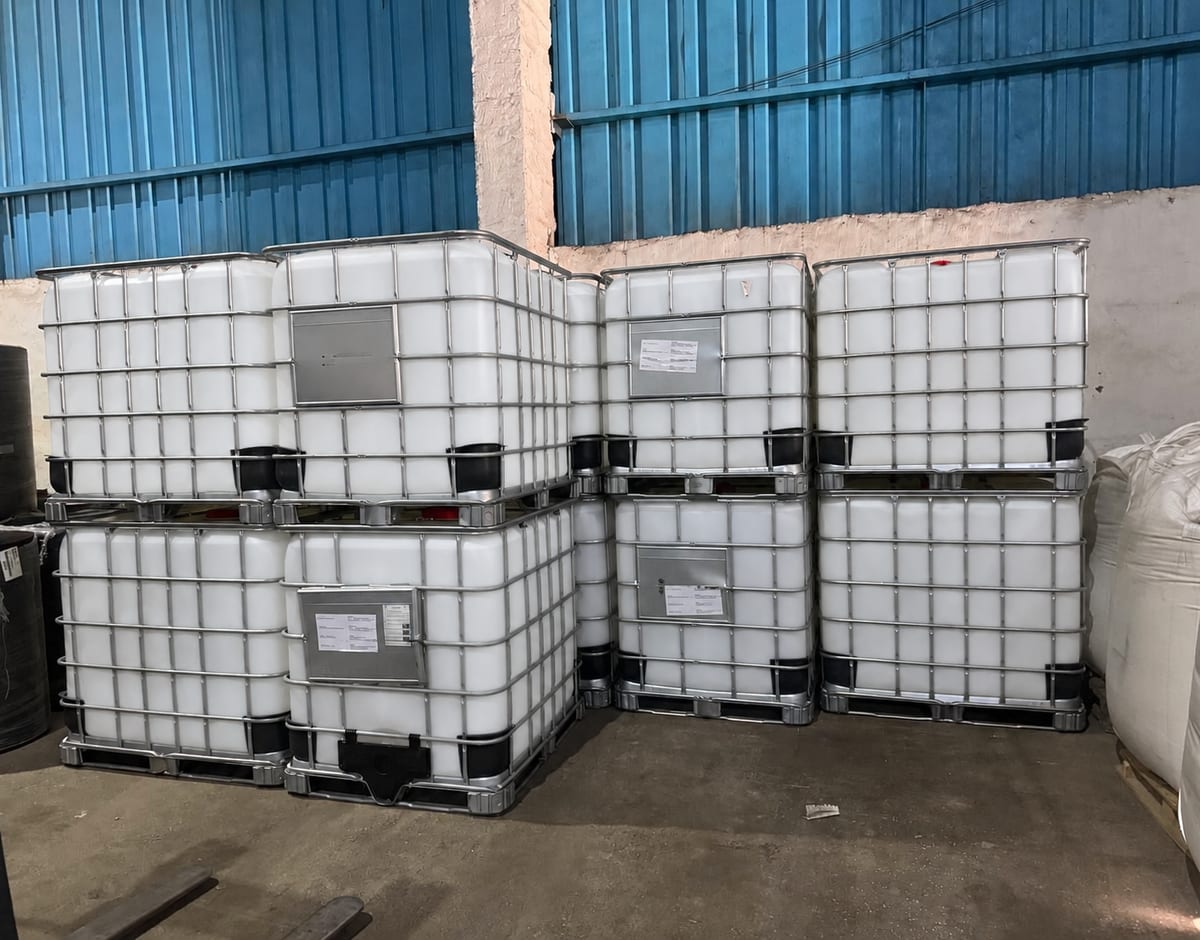 Белые пластиковые баки в металлических IBC-каркасах на складе
